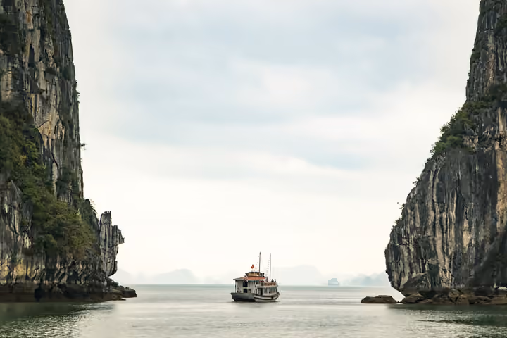 Bateau naviguant entre les falaises calcaires de la baie d’Ha Long