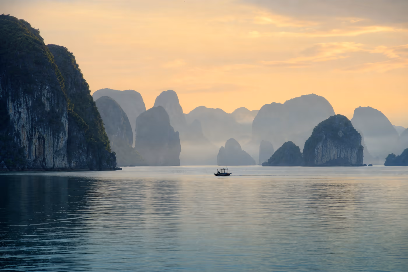 Baie calme bordée de formations karstiques dans la brume au Vietnam
