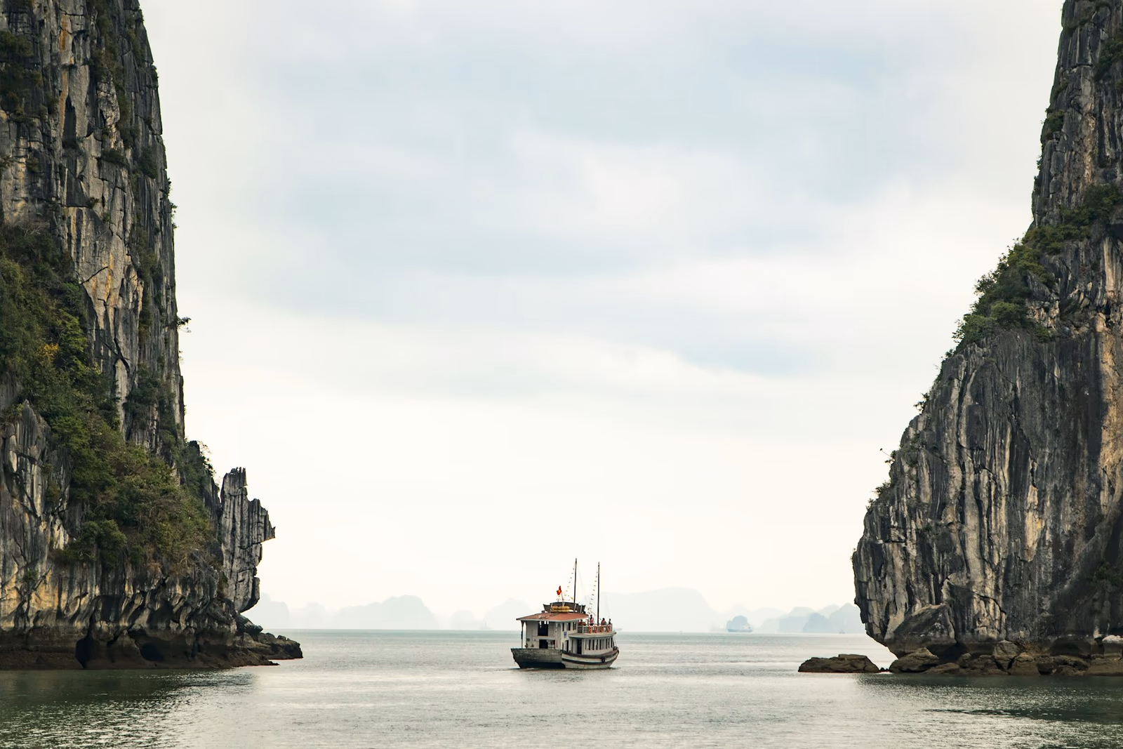 Bateau naviguant entre les falaises calcaires de la baie d’Ha Long