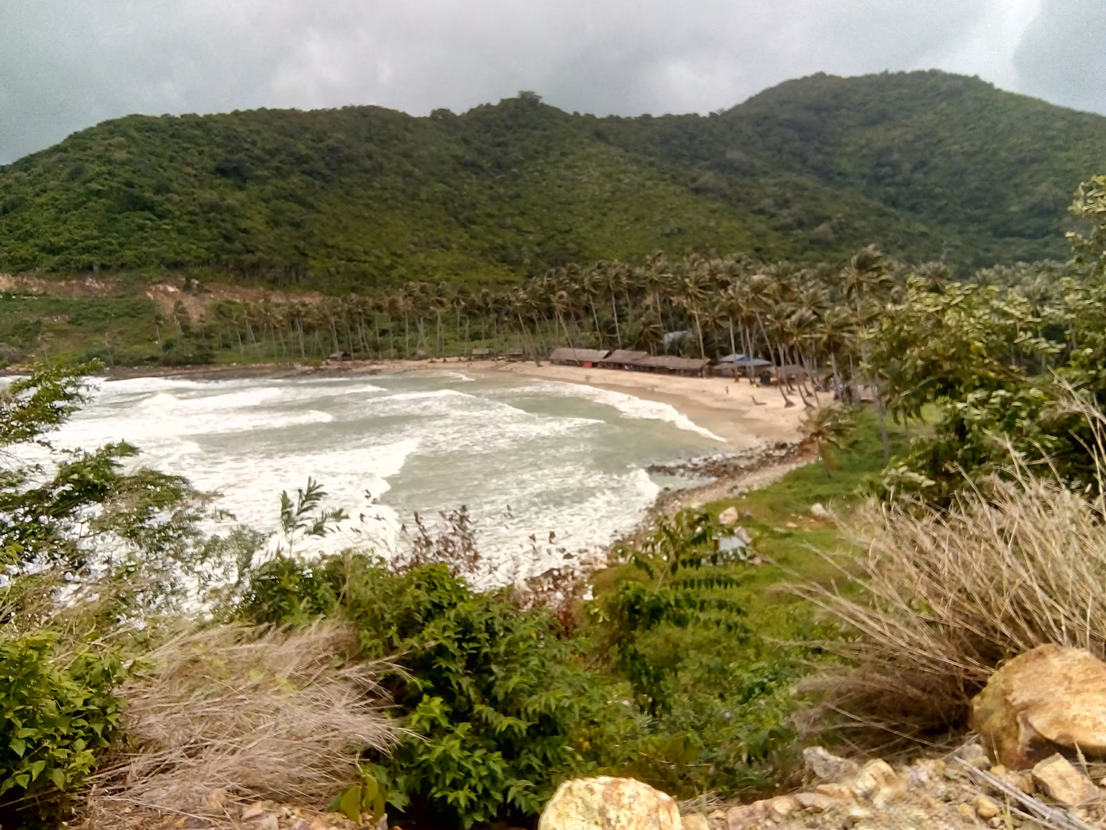 Côte rocheuse, maisons et végétation sur l’île de Nam Du