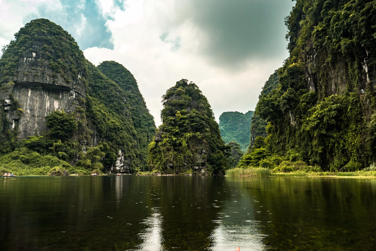 Barque avançant sur une rivière entre les falaises de Ninh Bình