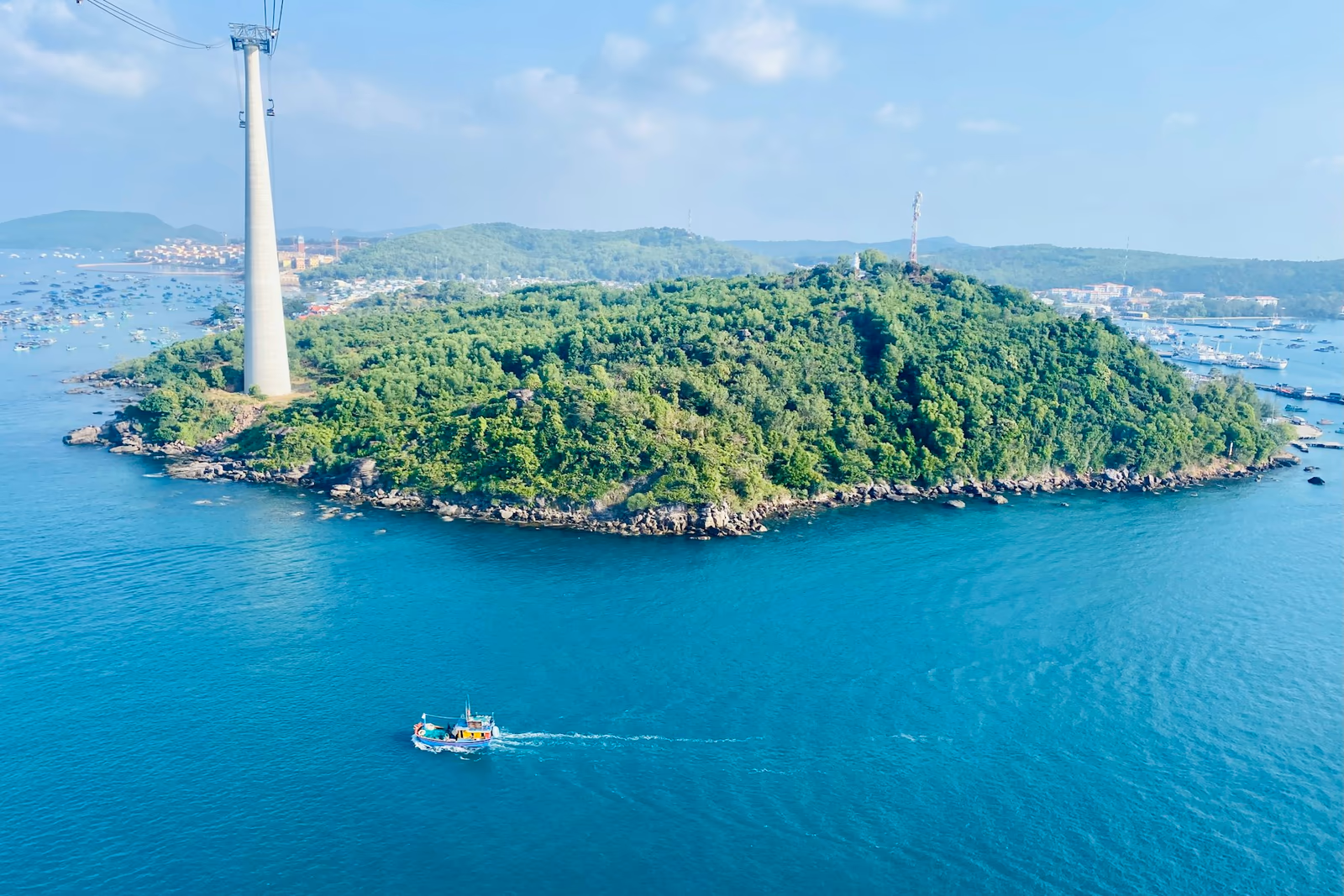 Île boisée, phare et bateaux dans les eaux de Phú Quốc